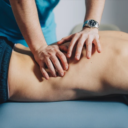 Hands applying manual therapy to a person’s lower back