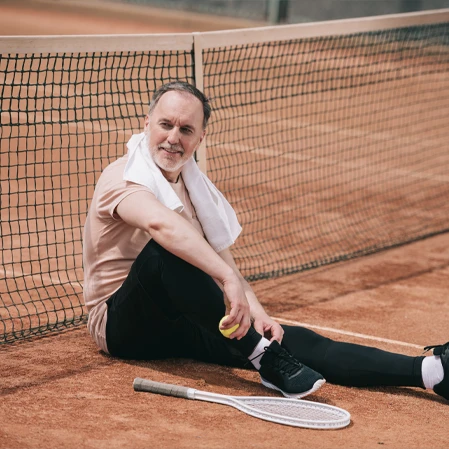 Person sitting on a clay tennis court